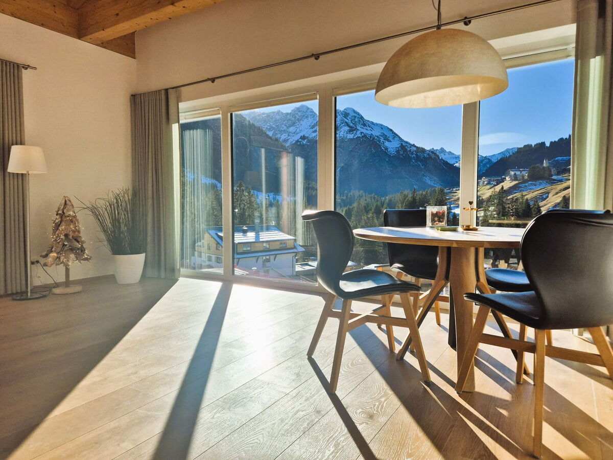 Dining table in front of the panorama windows with a view of the snow-covered mountains in the Panorama luxury lodge Ifen in the Kleinwalsertal