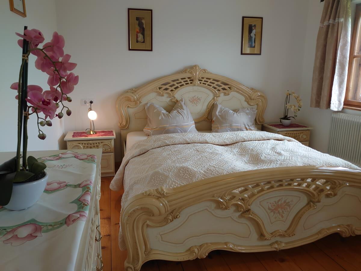 Bedroom in the Grafenhäusl with a white baroque bed and an orchid, the countess's former summer residence in Tyrol
