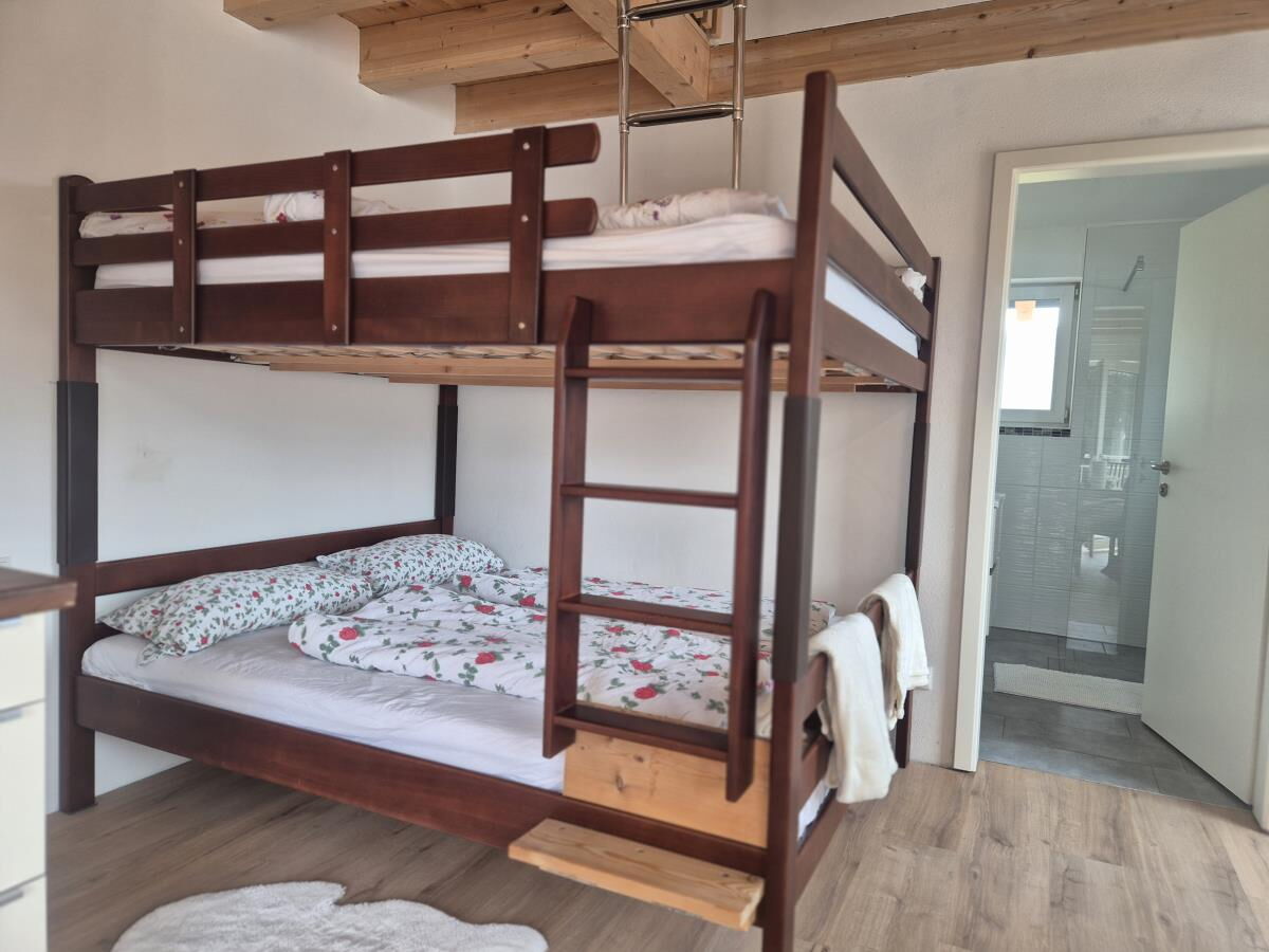 Massives Stockbett aus Holz in der Ferienwohnung Sternenhimmel am Kolsassberg, dahinter der Zugang zum Badezimmer, Platz für Familien und Kinder