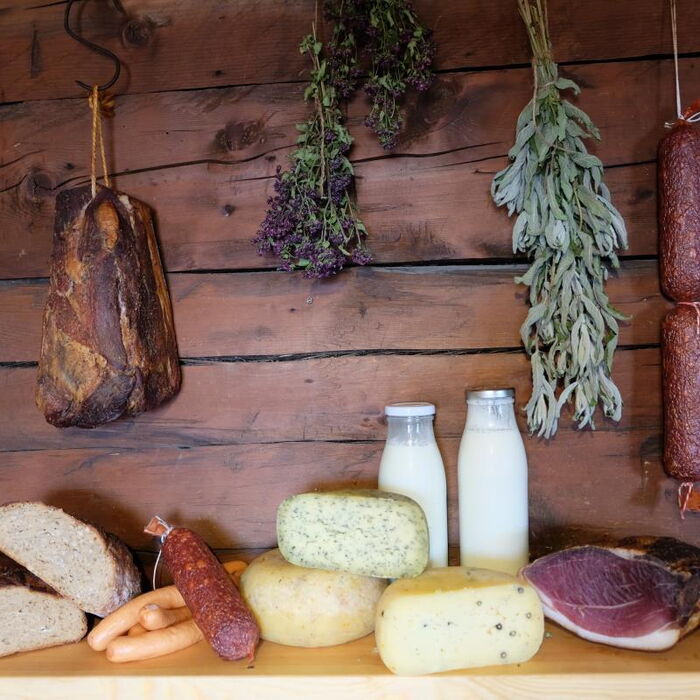 Tiroler Brettljause mit Speck, Käse, Brot und frischer Milch vor der Holzwand, regionale Jause an der Tiroler Hütte am Karwendel