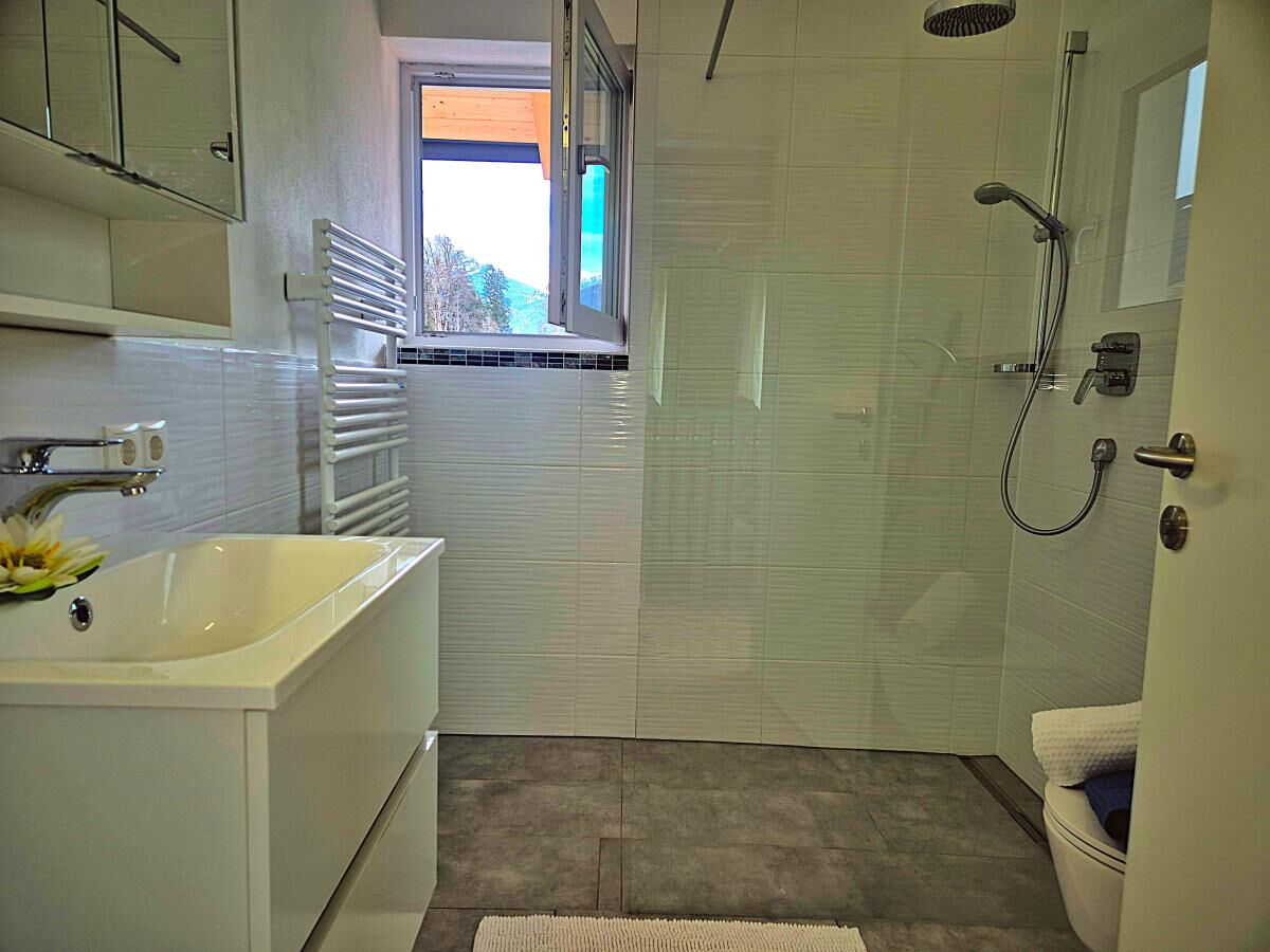 Modernes Badezimmer mit großzügiger Glasdusche, Waschbecken und Fenster in der Ferienwohnung Sternenhimmel am Kolsassberg