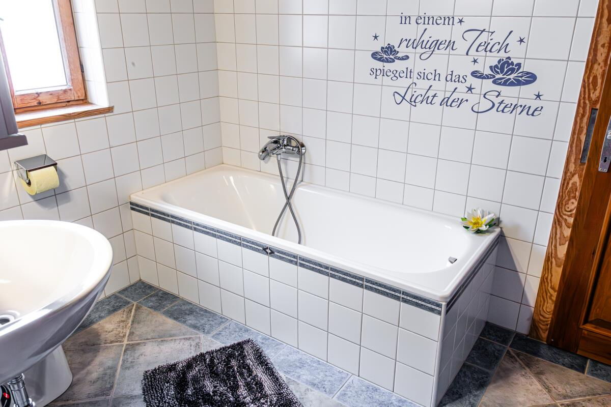 Bathroom in the Grafenhäusl with bathtub and a saying on the wall, holiday house for families on the Umlberg in Tyrol