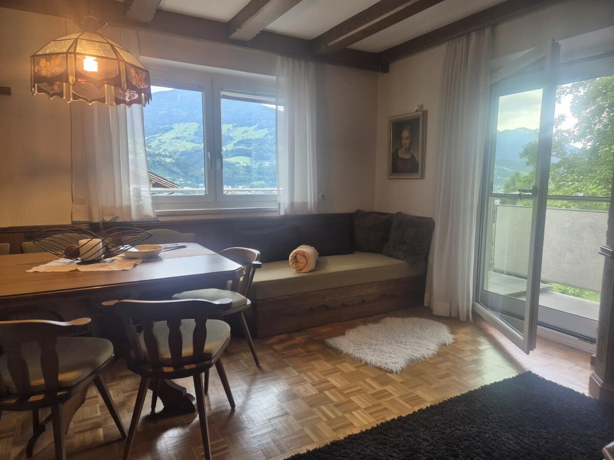 Wohnraum der Ferienwohnung Sonnseitn Karwendel mit rundem Esstisch, Bank am Fenster und Tür zur Terrasse