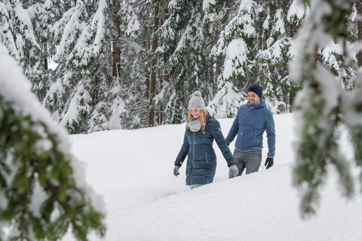 Couple on a winter hike through the deeply snow-covered forest near the Karwendel, a winter experience from the secluded Tiroler Hütte