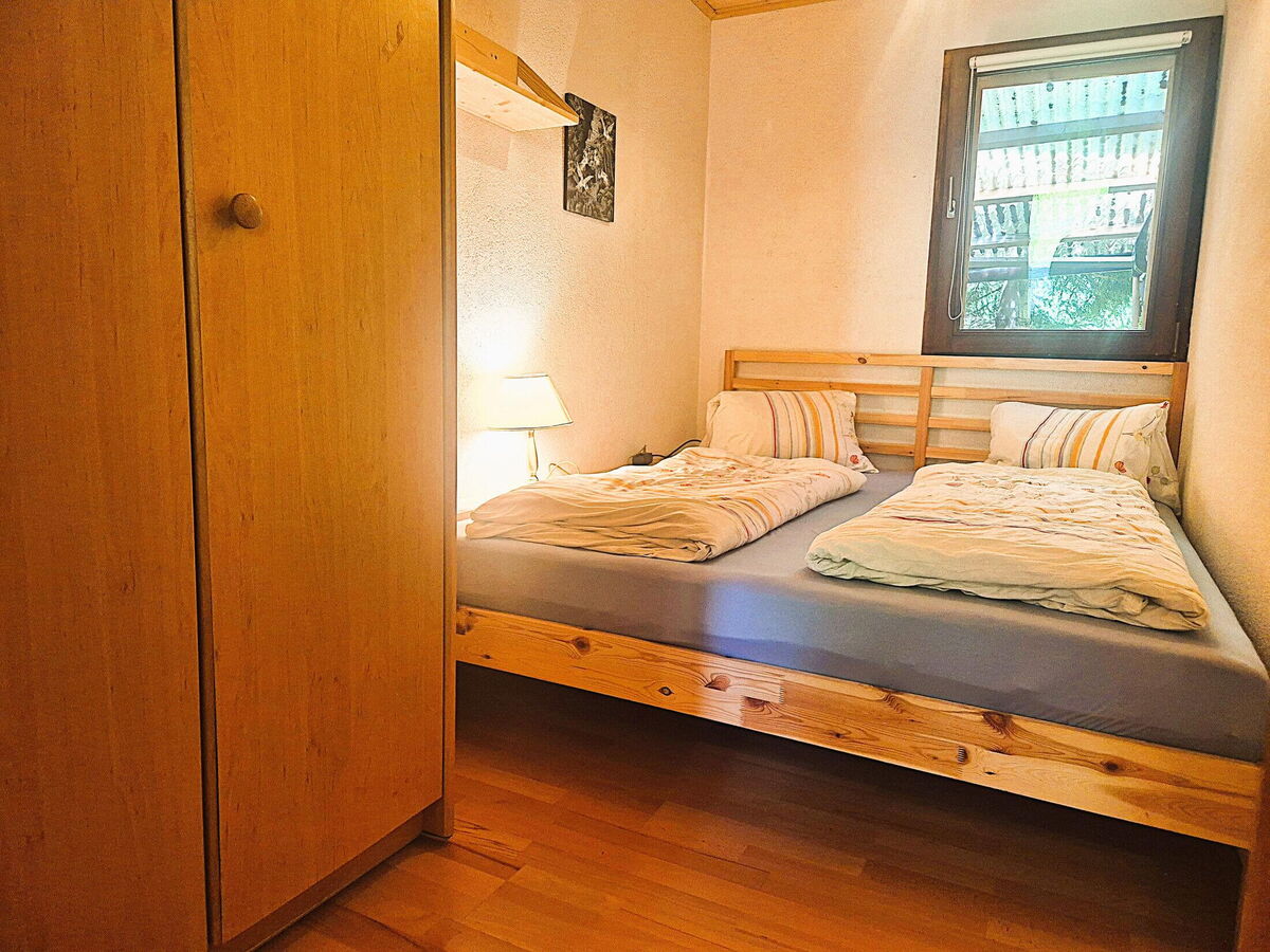 Schlafzimmer mit Holzbett, Kleiderschrank und Nachtlicht im Kochhäusl am Wattenberg, Berghütte für zwei bis vier Personen in Tirol