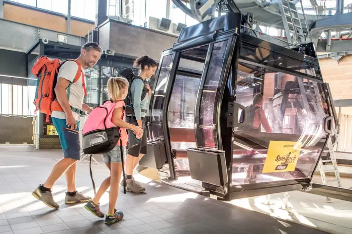 Family with rucksacks boarding the red gondola of the Spieljochbahn in Fügen