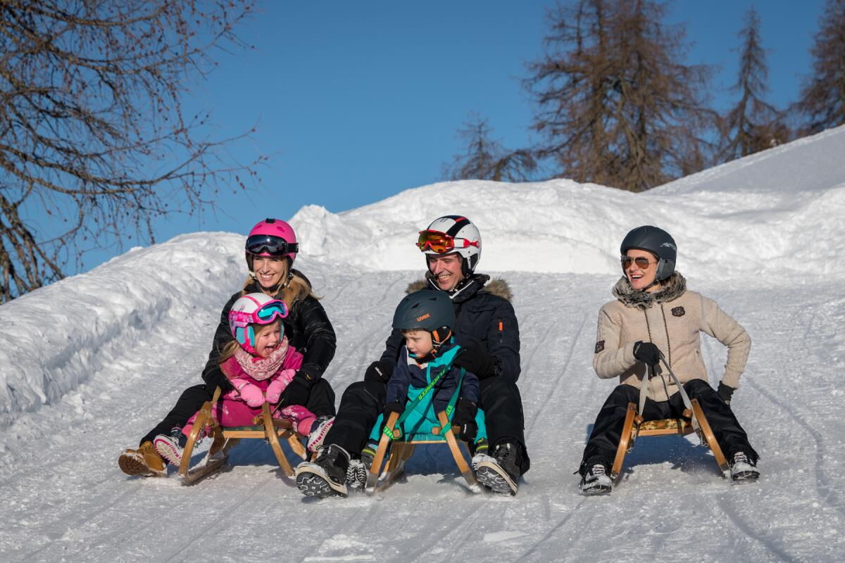 Family tobogganing near the Grafenhäusl, natural toboggan run in the Inn valley in Tyrol