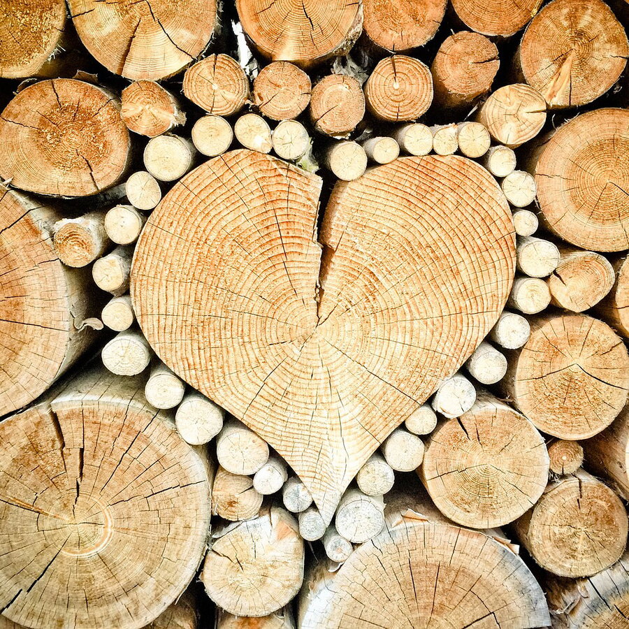 In mitten der Holzliehe ist ein Herz aus Holz in der Mitte zur Dekoration mit kleinen Ästen umrandet.