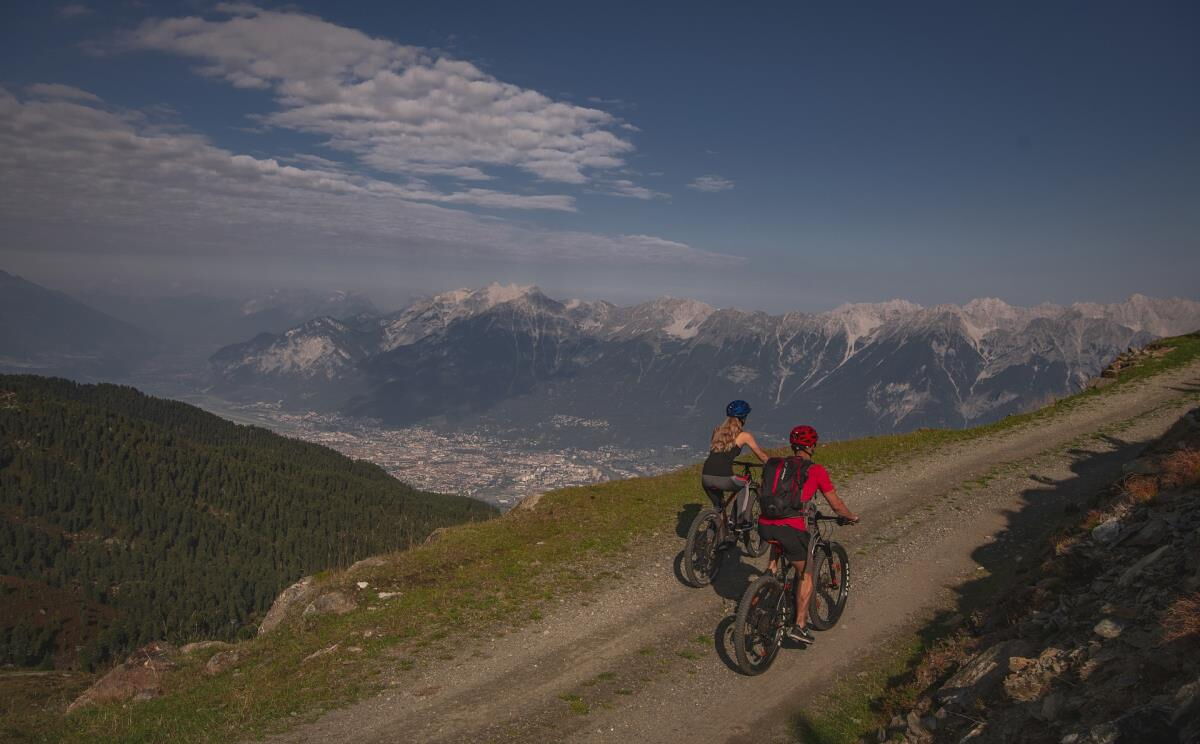 Zwei Mountainbiker auf dem Schotterweg über dem Inntal in den Tuxer Alpen, Radtour ab dem Kochhäusl am Wattenberg