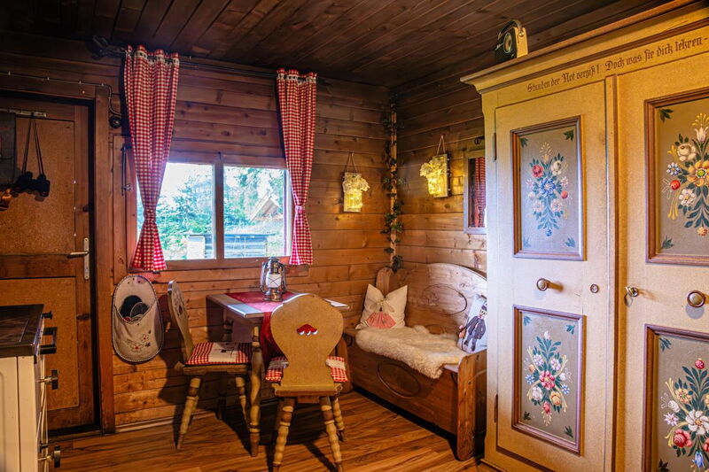 Tyrolean parlour with a painted farmhouse cupboard, wooden bench and red-and-white checked curtains