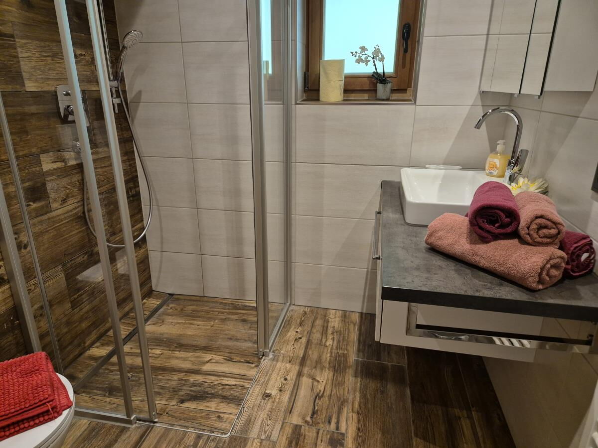 Modern bathroom with walk-in glass shower, washbasin and towels in the Tiroler Hütte near the Karwendel range