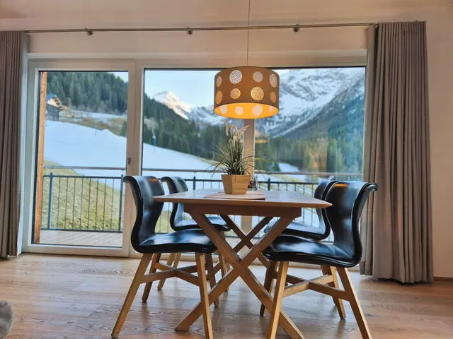 Blick vom Esstisch über den Süd-Balkon auf die verschneiten Alpenwiesen und Berge in der Bergwiese-Luxuslodge Zwölferkopf, Luxuslodge für 6 Personen im Kleinwalsertal