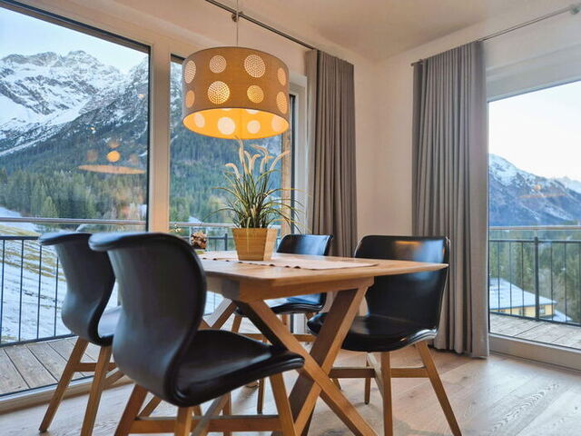 Esstisch aus Massivholz vor der Balkontür mit Blick auf die Berge in der Bergwiese-Luxuslodge Zwölferkopf, Ferienwohnung für Familien und Freunde im Kleinwalsertal