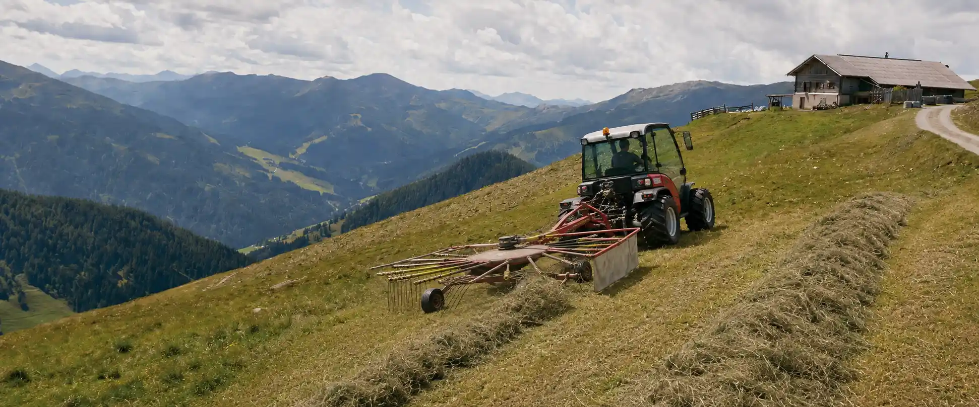 Hay harvest on a steep mountain meadow (Bergmahd) with two-axle mower and hay rake, Alm building at the edge of the slope
