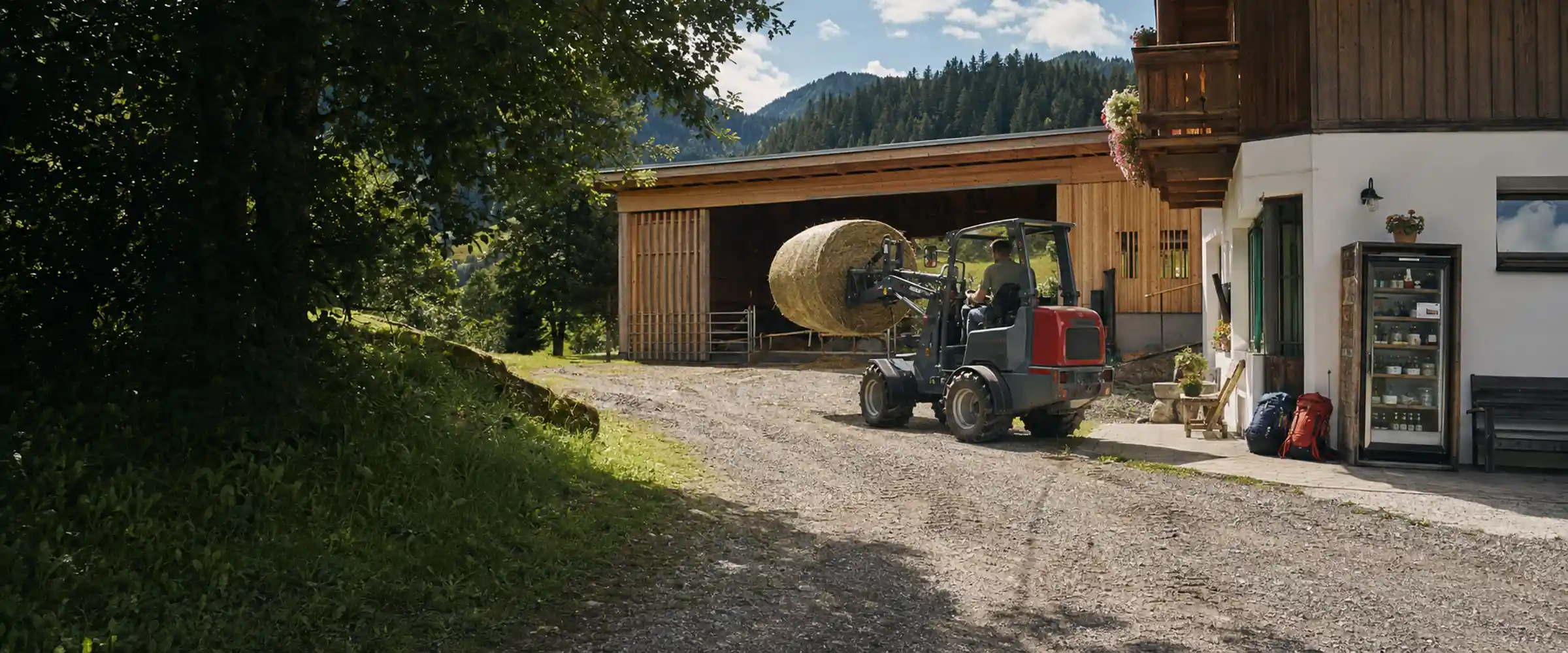 Farm loader with round bales in front of the barn, next to it a sales fridge and guests' backpacks