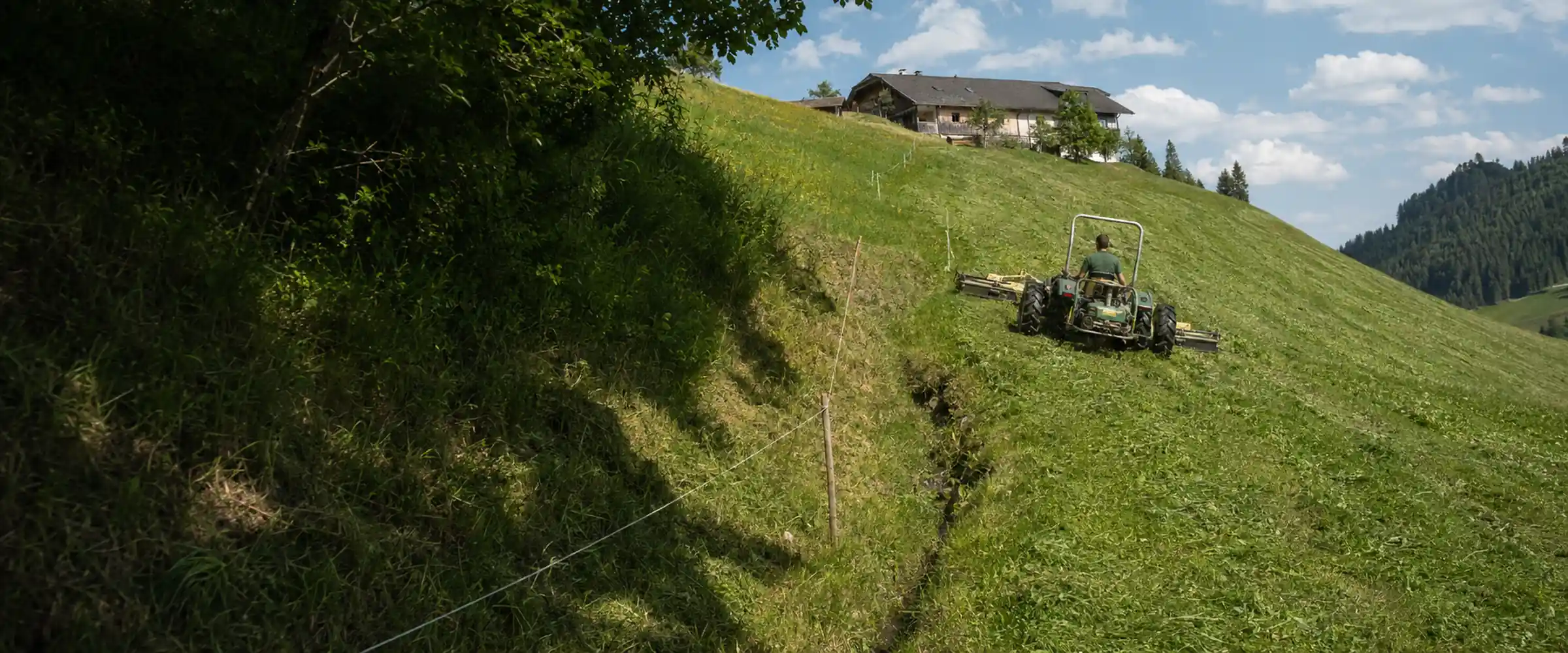 Mowing a steep mountain meadow with a two-axle mower, farm at the upper edge of the slope